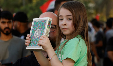 A child holds the Qur’an during a protest near the Green Zone against the burning of a copy of the Quran in the Swedish capital.