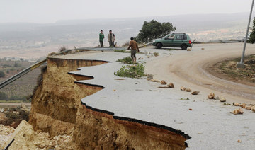 People stand in a damaged road as a powerful storm and heavy rainfall flooded hit Shahhat city, Libya, September 11, 2023. (REUT