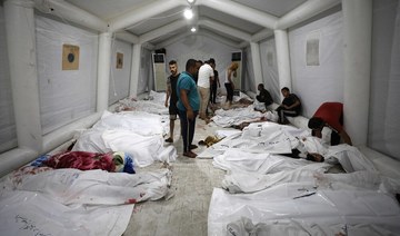 People stand over bodies of Palestinians killed in Israeli airstrikes on the Ahli Arab hospital in central Gaza.