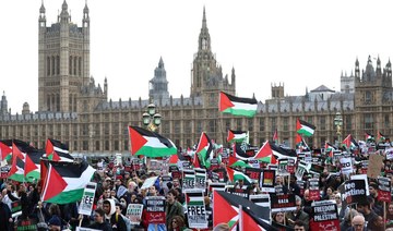 Protesters hold placards and wave Palestinian flags as they walk over Westminster Bridge.