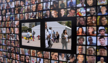 Passersby are reflected by mirrors on a poster with photographs of hostages abducted by Hamas militants in Tel Aviv, Israel.