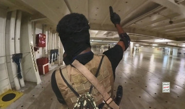 A Houthi fighter holds up a pistol in the cargo area of the Galaxy Leader cargo ship in the Red Sea in this photo.