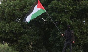 A man holds a Palestinian flag as mourners gather during the funeral of deputy head of Hamas, Saleh Al-Arouri. (AFP)