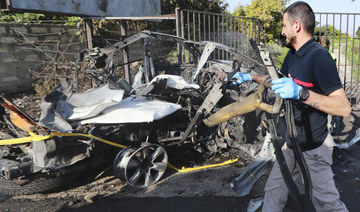 A civil defense worker carries parts of a destroyed car in the southern town of Bazouriyeh, Lebanon, Saturday, Jan. 20, 2024. 