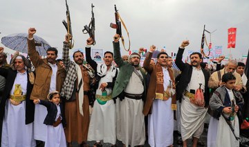 People lift rifles and placards as they chant during a Houthi rally in Sanaa on January 19, 2024. (AFP)