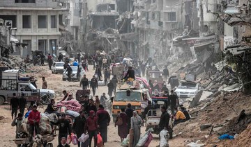 Displaced Palestinians carry their belongings through a street in Khan Yunis in the southern Gaza Strip on March 6, 2024. (AFP)