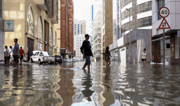 People walk through flood water caused by heavy rains, in Dubai, United Arab Emirates, April 17, 2024. (Reuters)