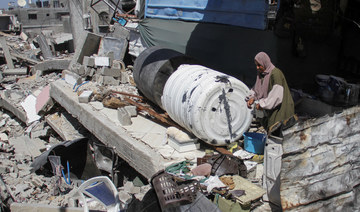 A Palestinian woman stands among the rubble of a damaged building, which was destroyed during Israel’s military offensive.