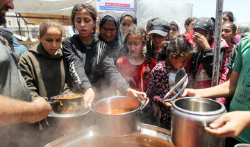 Palestinians gather on Wednesday to receive food cooked by a charity kitchen in Khan Younis, southern Gaza Strip. (Reuters)