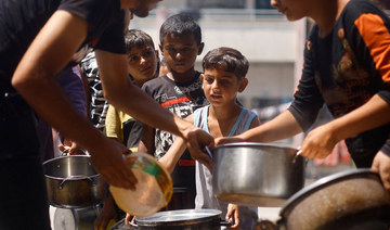 Palestinian children gather to receive food cooked by a charity kitchen, amid food scarcity in Khan Younis.