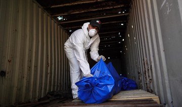 A man removes bodies from a container after they were taken and later released by Israel, ahead of a mass funeral at a cemetery.