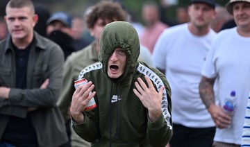 Protester gestures at riot police as clashes erupt in Bristol on August 3, 2024 during the “Enough is Enough” demonstration.
