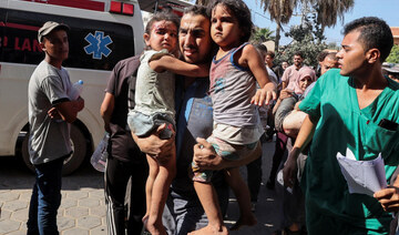 A Palestinian man carries children wounded in an Israeli strike at Al-Aqsa Martyrs Hospital in Deir Al-Balah.