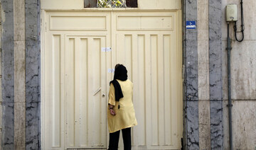 A woman reads the Iranian police closure notice on the gate of a language institute certified by German embassy, in Tehran, Iran