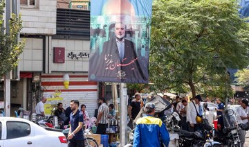 People walk past a banner featuring a picture of the late Hamas political leader Ismail Haniyeh.