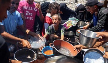 A child reacts as people gather to receive meals during food distribution from a kitchen in the Bureij camp for refugees. 