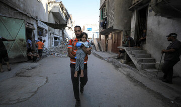 A civil defence worker carries a girl at a school site, which was sheltering displaced people,after it was hit by Israeli strike