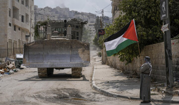 A man waves the Palestinian flag as a convoy of Israeli military bulldozers drive by during an army raid in Jenin, West Bank.