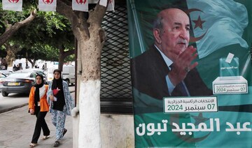 People walk past posters of Algeria’s President Abdelmajid Tebboune outside an election campaign headquarters in Algiers.