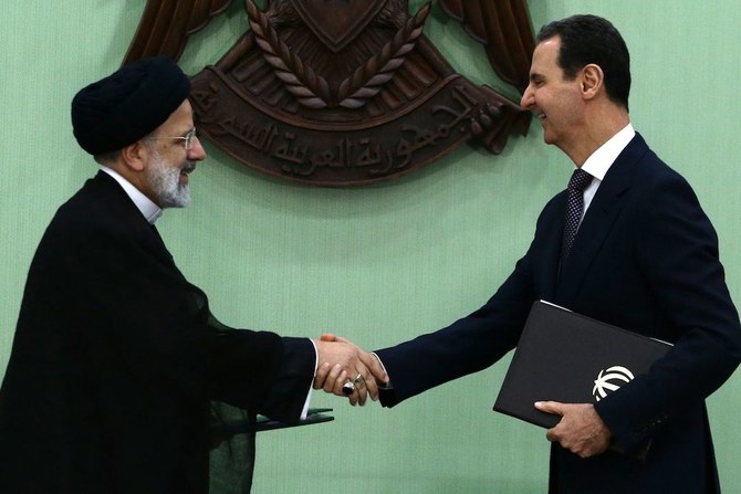 Syria’s President Bashar Assad (R) and his Iranian counterpart Ebrahim Raisi shake hands after signing a memoranda of understanding on “long-term strategic cooperation” in Damascus on May 3, 2023. (AFP)