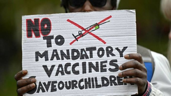 A protester holds up a placard at a demonstration in London in October against mandatory vaccinations. A leading Muslim scholar in Canada warned people not to believe conspiracy theories about the coronavirus vaccine. (AFP/File Photo)