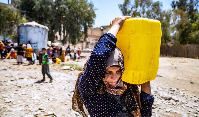 A Syrian woman carries a container of water provided by UNICEF in Hasakeh after supply disruption. (AFP)