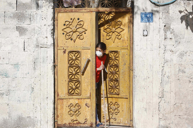 A girl wearing a protective N95 mask sweeps outside her home in Gaza City. (AFP file photo)