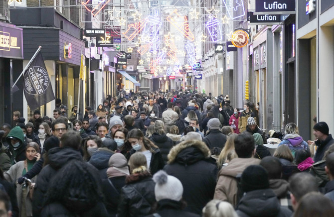 Crowds of people walk down a street on the last Saturday before Christmas in Amsterdam, the Netherlands, Saturday, Dec. 18, 2021. (AP)