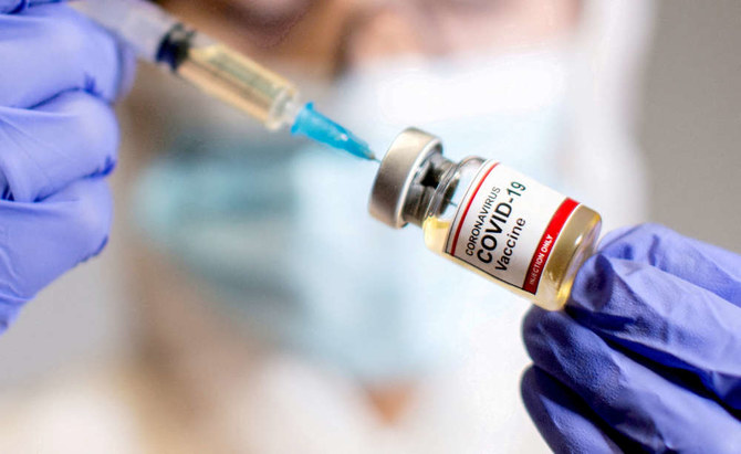 A woman holds a small bottle labelled with a "Coronavirus COVID-19 Vaccine" sticker and a medical syringe. (REUTERS file photo)