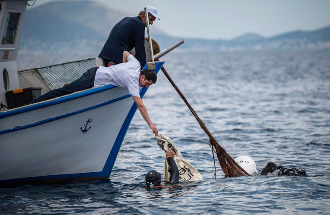 Divers and volunteers collect ghost nets under the water during a cleanup operation near the coast of the Island of Salamina. 