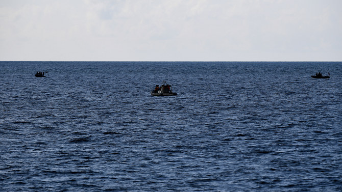 Chinese coast guard personnel (C) aboard their rigid hull inflatable boat observing Philippine coast guard personnel.