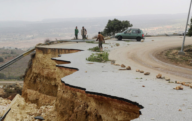 People stand in a damaged road as a powerful storm and heavy rainfall flooded hit Shahhat city, Libya, September 11, 2023. (REUT