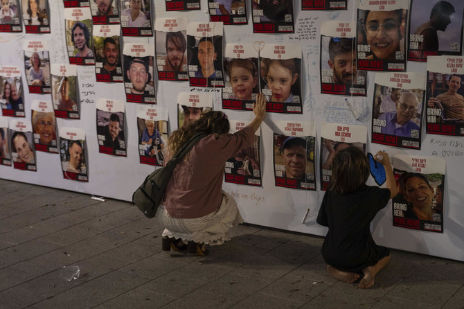 An Israeli woman touches photos of Israelis missing and held captive in Gaza, displayed on a wall in Tel Aviv. (AP)