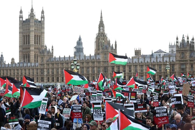 Protesters hold placards and wave Palestinian flags as they walk over Westminster Bridge.