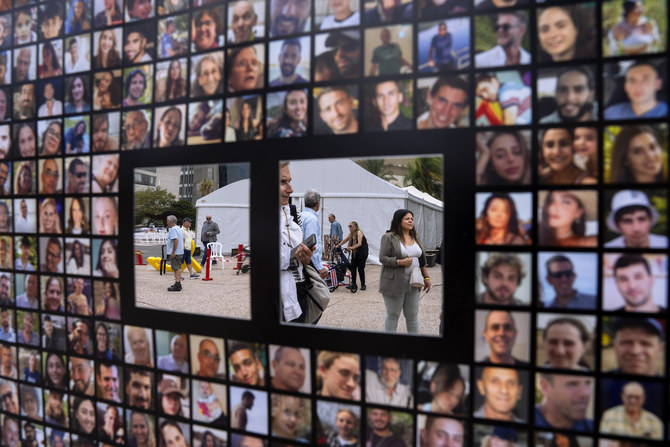 Passersby are reflected by mirrors on a poster with photographs of hostages abducted by Hamas militants in Tel Aviv, Israel.