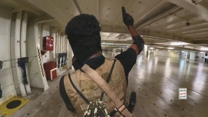 A Houthi fighter holds up a pistol in the cargo area of the Galaxy Leader cargo ship in the Red Sea in this photo.