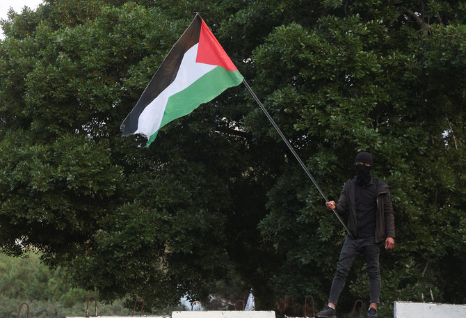 A man holds a Palestinian flag as mourners gather during the funeral of deputy head of Hamas, Saleh Al-Arouri. (AFP)