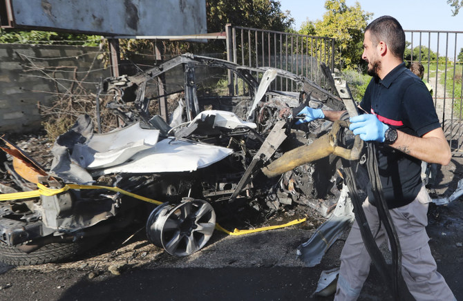 A civil defense worker carries parts of a destroyed car in the southern town of Bazouriyeh, Lebanon, Saturday, Jan. 20, 2024. 