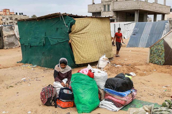A woman sits by packed belongings near a tent at a camp before fleeing from Rafah in the southern Gaza Strip.