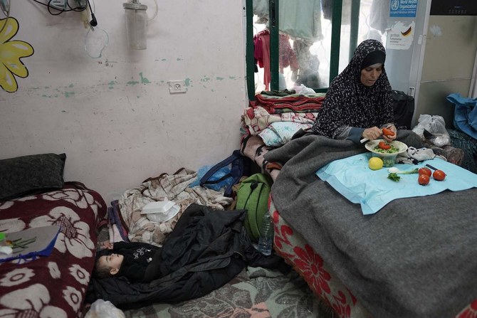 A Palestinian woman cuts vegetables near a sleeping boy at the Shuhada Al-Aqsa Hospital in Deir El-Balah.