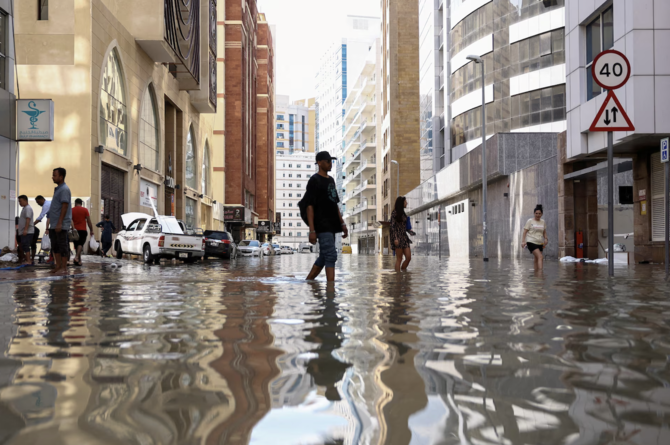 People walk through flood water caused by heavy rains, in Dubai, United Arab Emirates, April 17, 2024. (Reuters)