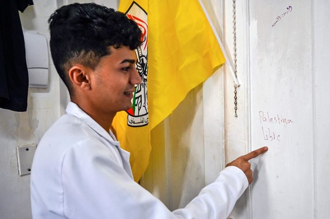 Motee Al-Mashar, 24, points to handwriting he made on a wall that reads "Free Palestine" at his apartment in Havana.