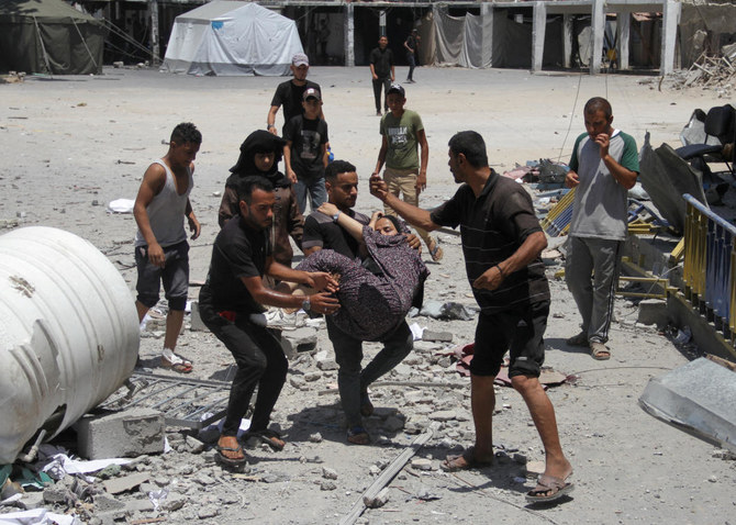 Palestinians carry a casualty outside the headquarters of UNRWA following an Israeli strike, amid the Israel-Hamas conflict.