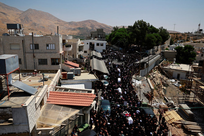 Mourners carry coffins, during the funeral of children who were killed at a soccer pitch by a rocket fired from Lebanon.