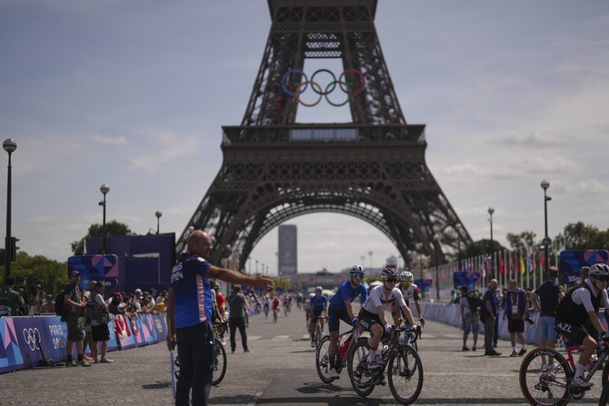 Cyclists arrive by the Eiffel Tower, ahead of the start of the women's road cycling event, at the 2024 Summer Olympics, Sunday, 