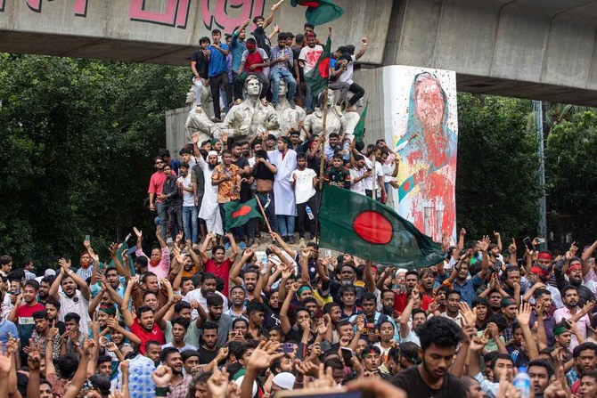 Protesters climb a public monument as they celebrate the news of Prime Minister Sheikh Hasina’s resignation, in Dhaka.