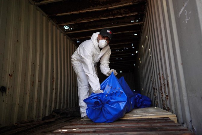 A man removes bodies from a container after they were taken and later released by Israel, ahead of a mass funeral at a cemetery.