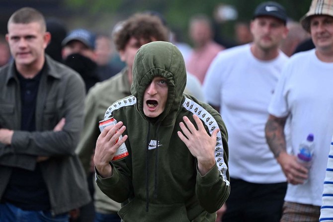 Protester gestures at riot police as clashes erupt in Bristol on August 3, 2024 during the “Enough is Enough” demonstration.