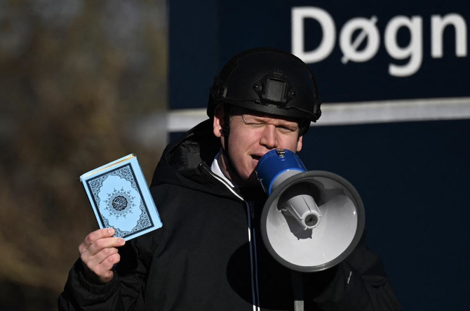 Far-right politician Rasmus Paludan holds up a copy of the Qur’an as he speaks in front of a mosque in Copenhagen. (File/AFP)