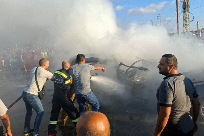 Civil defense members hose down a car after an Israeli airstrike targeted a car on the edge of Lebanon’s port city of Sidon.